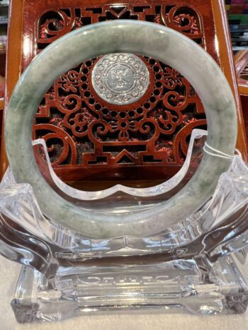 A large green jade ring sitting on top of a glass table.