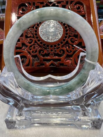 A circular stone carving on top of a clear glass stand.