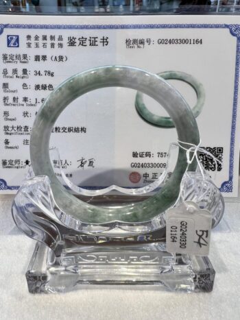 A green jade bangle is displayed in a glass case.