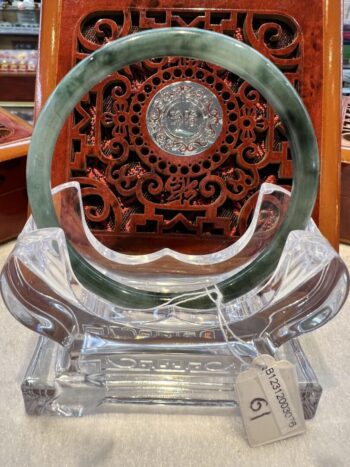 A green and white jade circular plaque on display.