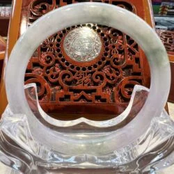 A white circular stone on display in front of an ornate wooden carving.