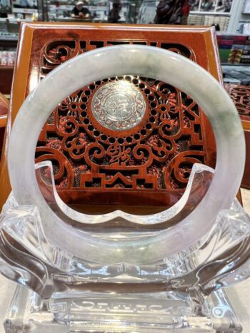 A white circular stone on display in front of an ornate wooden carving.