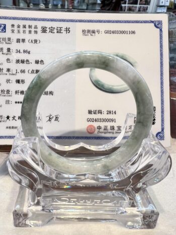 A large green jade bangle is displayed in front of an award.