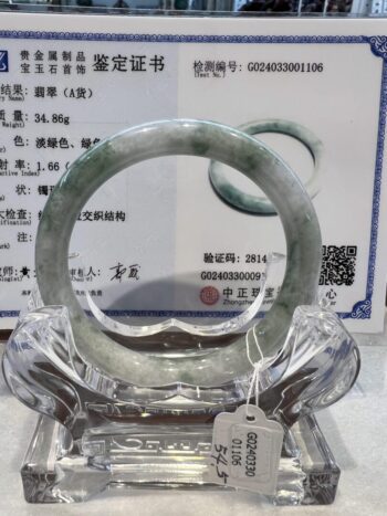 A green jade bangle sitting on top of a glass display.