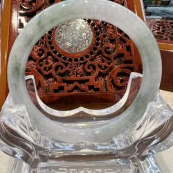 A large round green jade ring sitting on top of a glass stand.