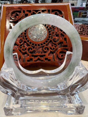 A large round green jade ring sitting on top of a glass stand.