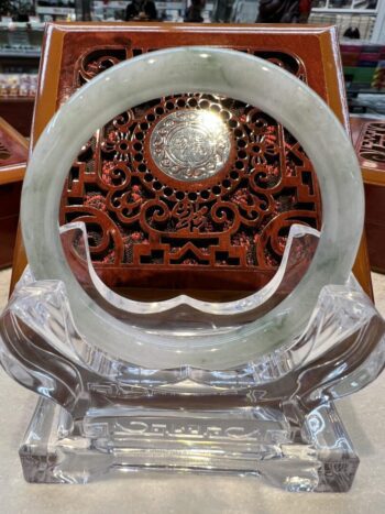 A round white stone on display in front of an ornate wooden carving.