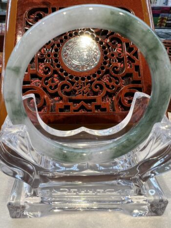 A large green jade ring sitting on top of a glass display.