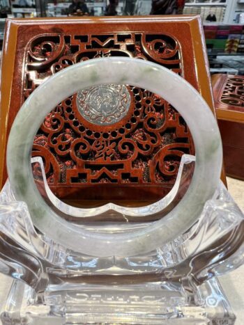 A large white jade ring sitting on top of a wooden chair.