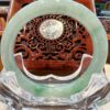 A green jade ring sitting on top of a clear glass bowl.