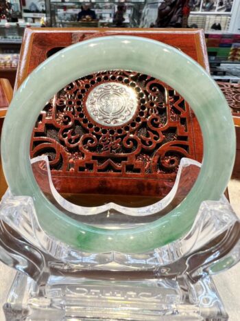 A green jade ring sitting on top of a clear glass bowl.