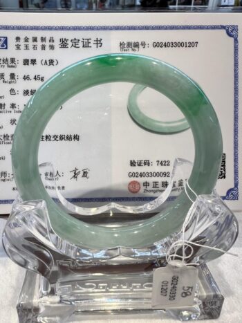 A green jade bangle is sitting on top of a glass plate.