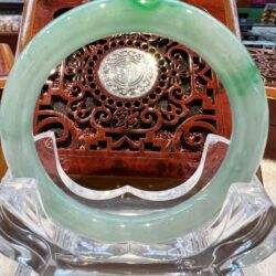 A green jade ring sitting on top of a clear glass vase.