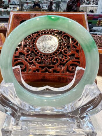 A green jade ring sitting on top of a clear glass vase.