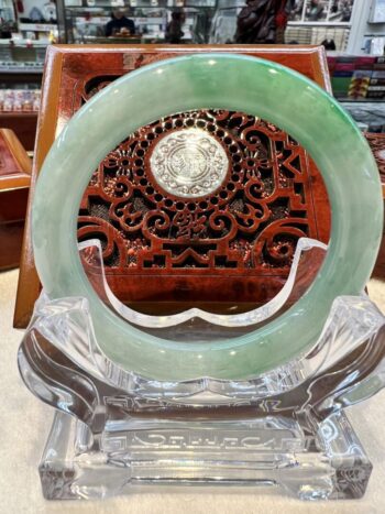 A green jade ring sitting on top of a clear glass plate.