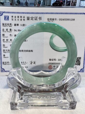 A green jade bangle is sitting on top of a glass plate.