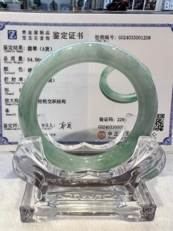 A green jade bangle is sitting on top of a glass table.