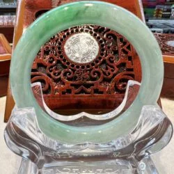 A green jade bangle sitting on top of a clear glass chair.