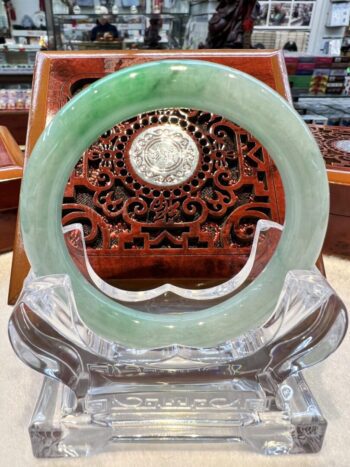 A green jade bangle sitting on top of a clear glass chair.