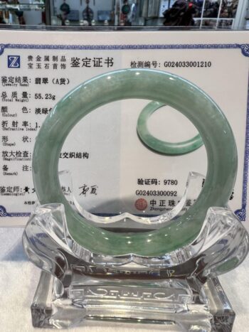 A green jade bangle is sitting on top of a certificate.