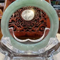 A green jade bangle sitting on top of a clear glass.