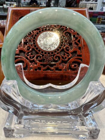 A round green stone plate sitting on top of a clear glass stand.