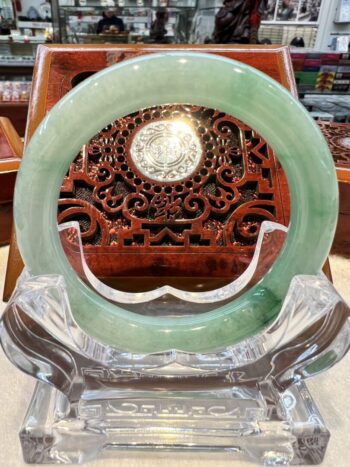 A green jade ring sitting on top of a clear glass.