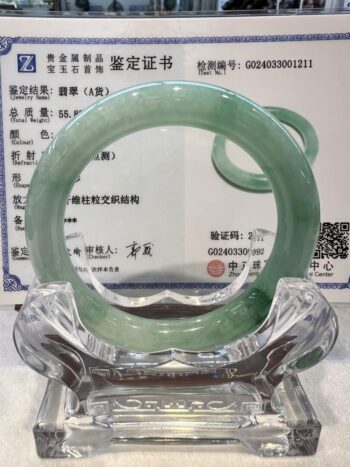 A green jade bangle is sitting on top of a glass plate.