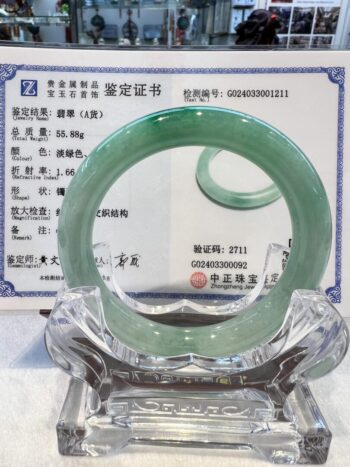 A green jade bangle is sitting on top of a certificate.