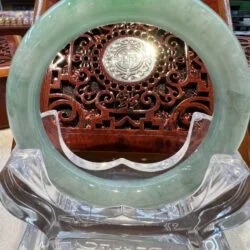 A round green stone is sitting in front of an ornate wooden carving.