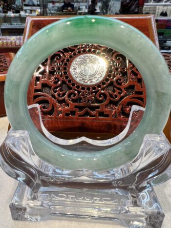 A round green stone is sitting in front of an ornate wooden carving.