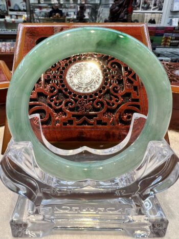 A green jade ring sitting on top of a clear glass.