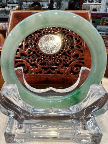 A green jade plate sitting on top of a clear glass dish.