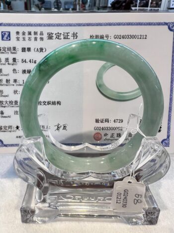 A green jade bangle is displayed in a glass case.