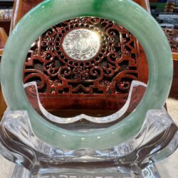 A green jade bangle sitting on top of a clear glass table.