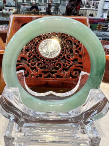 A green jade ring sitting on top of a clear glass plate.