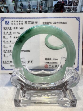 A green jade bangle is sitting on top of a certificate.