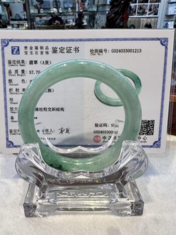 A green jade bangle is sitting on top of a glass plate.