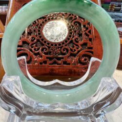 A green jade ring sitting on top of a clear glass display.