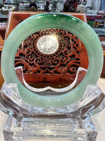 A green jade ring sitting on top of a clear glass display.