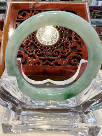 A green jade bangle sitting on top of a glass bowl.