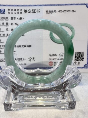 A green jade bangle is sitting on top of a glass stand.