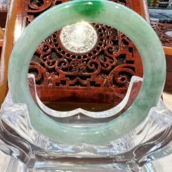 A green jade bangle sitting on top of a glass table.