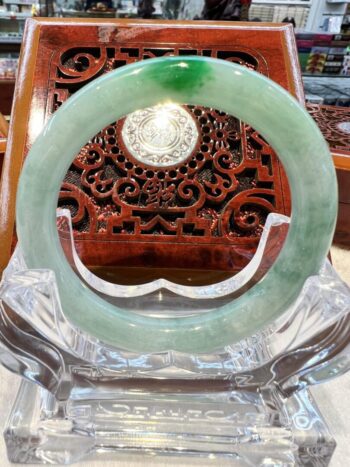 A green jade bangle sitting on top of a glass table.