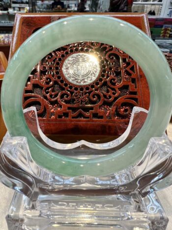 A green jade circle sitting on top of a clear glass.