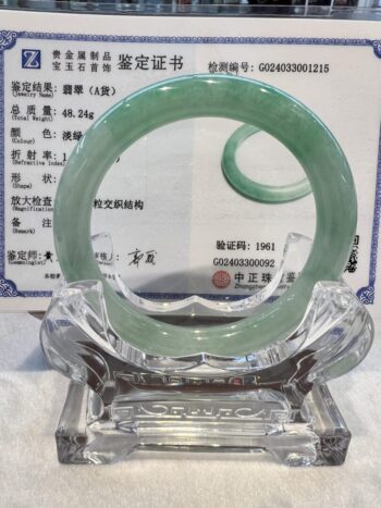 A glass sculpture of an open circle with green jade.