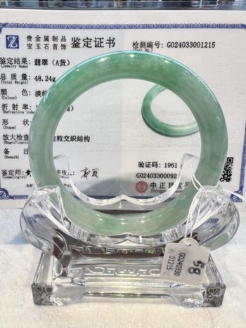 A green jade bangle is on display in front of an advertisement.