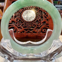 A green jade bangle sitting on top of a clear glass table.