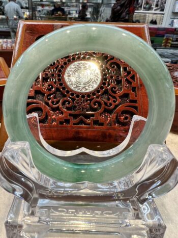 A green jade ring sitting on top of a clear glass plate.