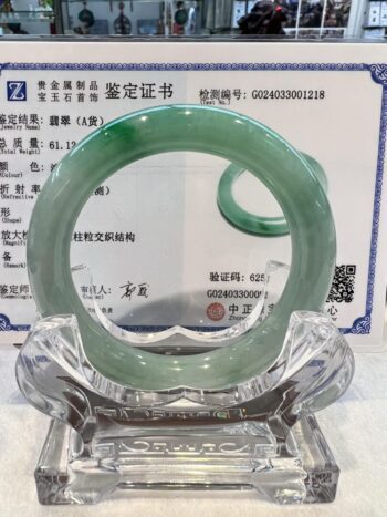 A green jade bangle is sitting on top of a glass plate.